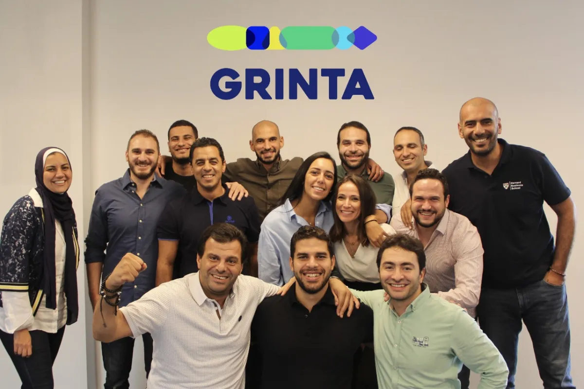 The Grinta team in the company's office, standing beneath the Grinta logo